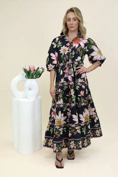 Woman wearing the Amelie Maxi dress standing next to a white vase with tulips on a beige background