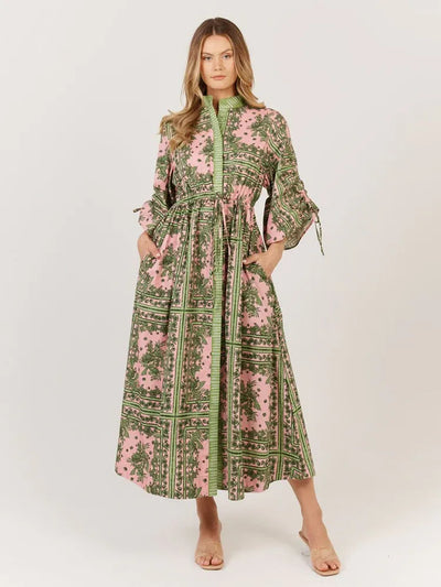 Woman wearing the Fate + Becker Dominica Dress in green and pink paisley print, button-down front with waist tie with hands in the pockets