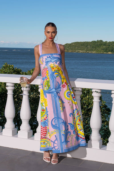 Front view of the Summer in Sicily Maxi Dress by Mia Milani – colourful linen maxi dress with empire line fit and cross-over straps, photographed by the ocean.