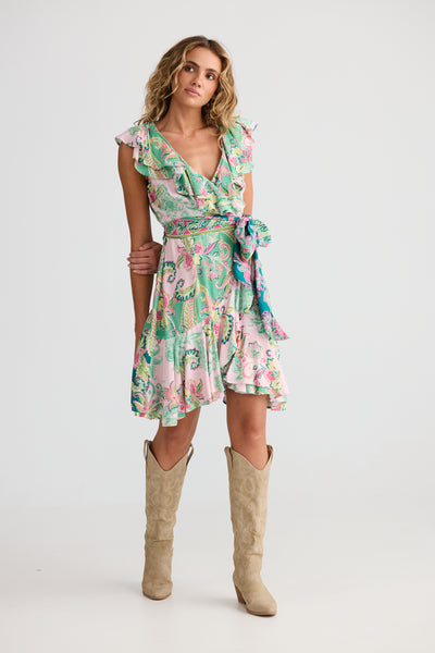 Woman wearing Pia Wrap Dress with beige knee-high boots on a white background