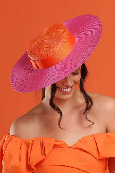 Model styling Domino Boater Pink Orange with orange dress – bold colour-blocked racewear outfit.