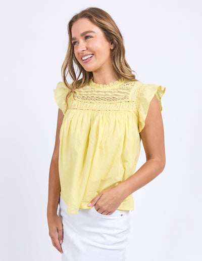 Side view of Foxwood Adelyn Top Yellow paired with white skirt