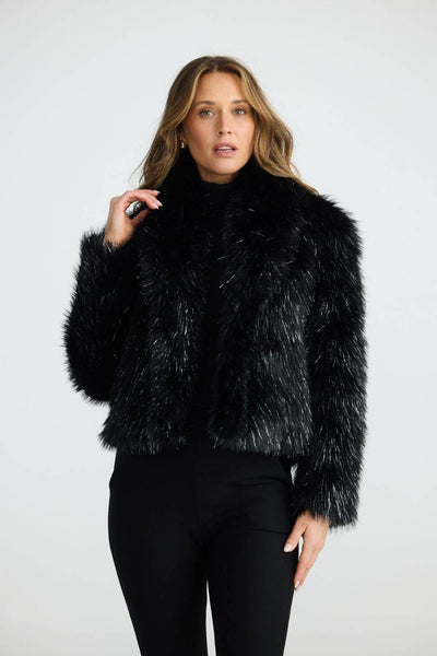 Front view of the Brave+True Glamour Fur Jacket Black Sparkle, paired with black pants.