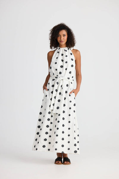 Model wearing Lucia Dress in Woven Spot Print from Shanty, front view, halter neck with waist tie, maxi length.