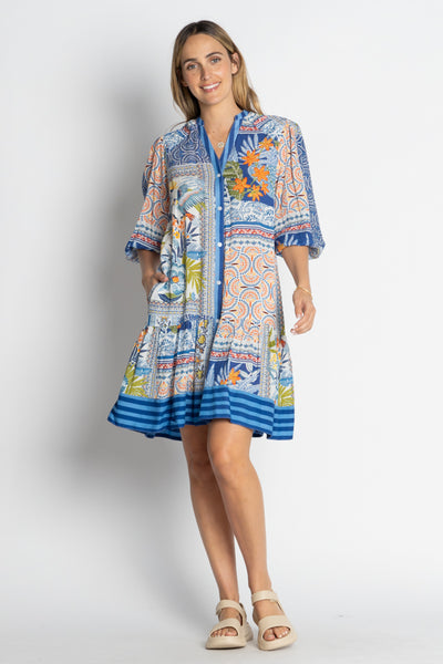 Model wearing the Velora Dress Ocean by Lulalife, a button-through, knee-length dress with pockets and blue ocean-inspired print