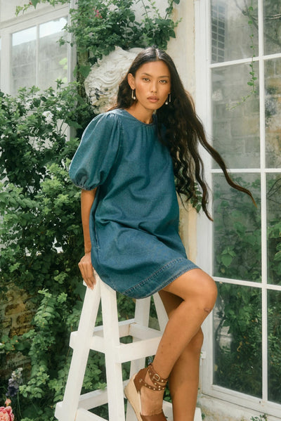 Sofie Denim Dress worn by model sitting on a stool